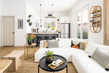 A living room with a white couch and a kitchen in the background